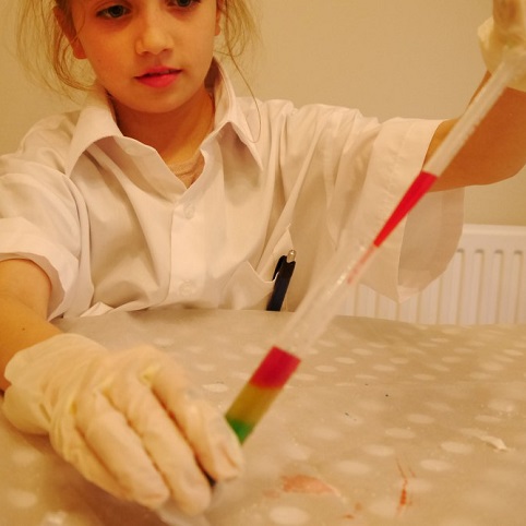 a girl making a liquid rainbow with letterbox lab science equipment