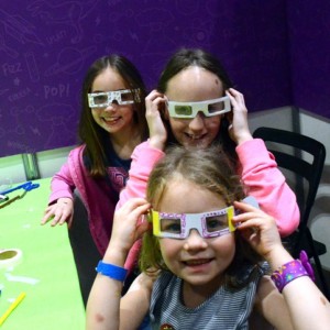 3 girls wearing letterbox lab's rainbow glasses from their first science kit